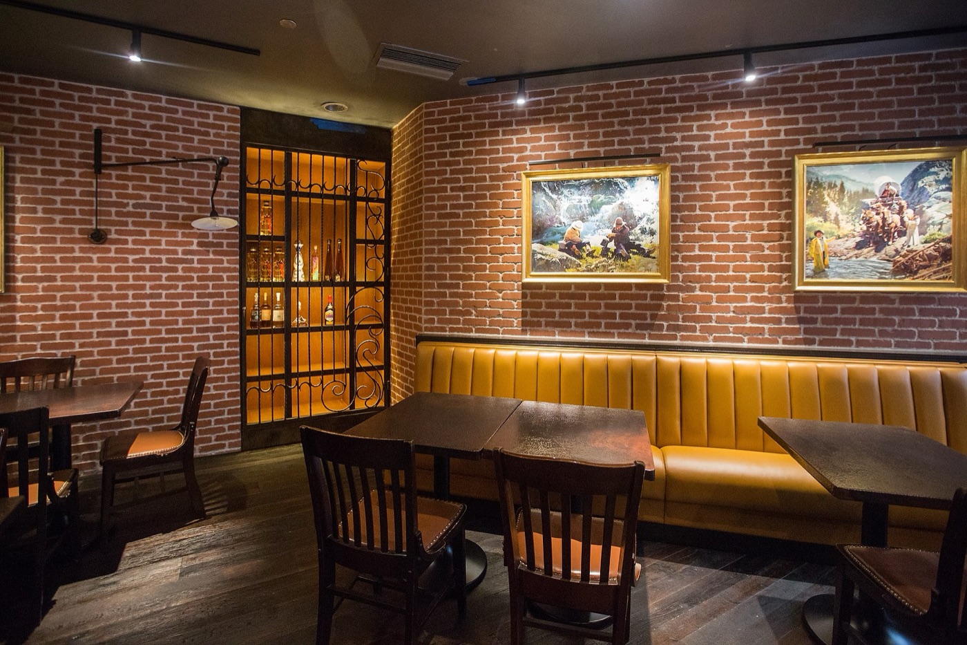 Framed artwork accent-lit on a brick wall in a restaurant dining room