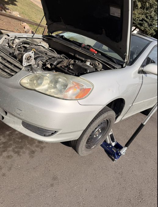 Mobile mechanic working on Toyota Corolla in driveway